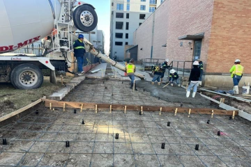 Workers pouring and testing the concrete at a construction site