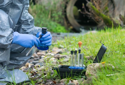A worker collecting water samples from a site for phase 2 environmental site assessment